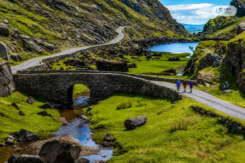 Scenic road and historic stone bridge along the Ring of Kerry surrounded by mountains and lakes in Ireland