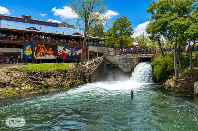 Scenic waterfall and riverside overlook near New Braunfels TX Landa Park with visitors enjoying the waterfront view.