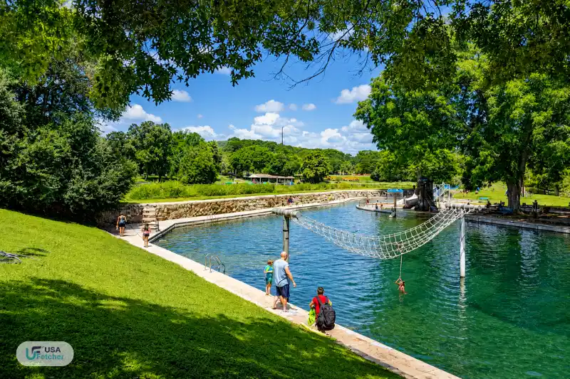 Spring-fed swimming area and rope play feature at New Braunfels TX Landa Park surrounded by lush green trees